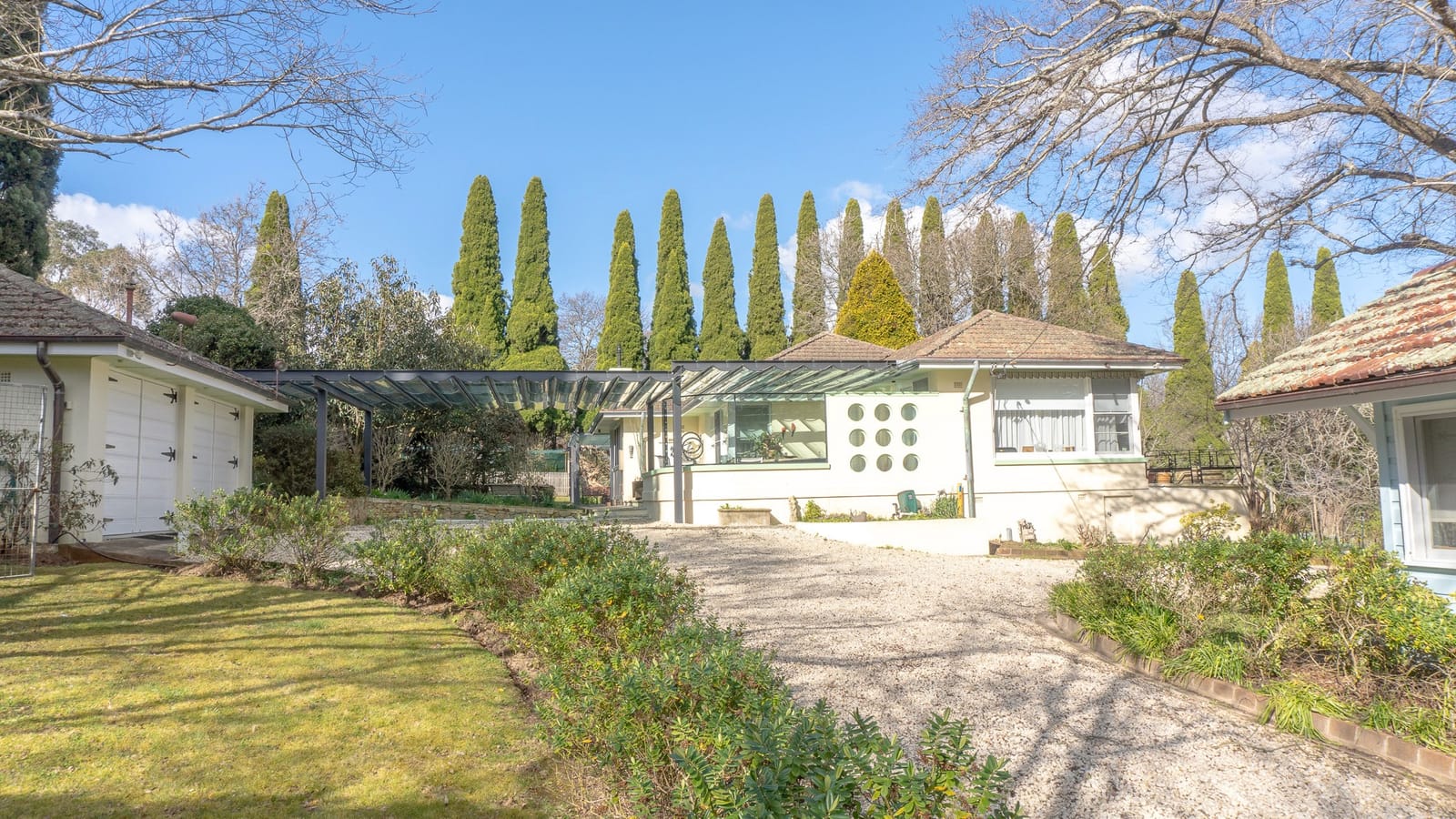 The lawn at Yarrabin running toward a long pergola and the white garage building.